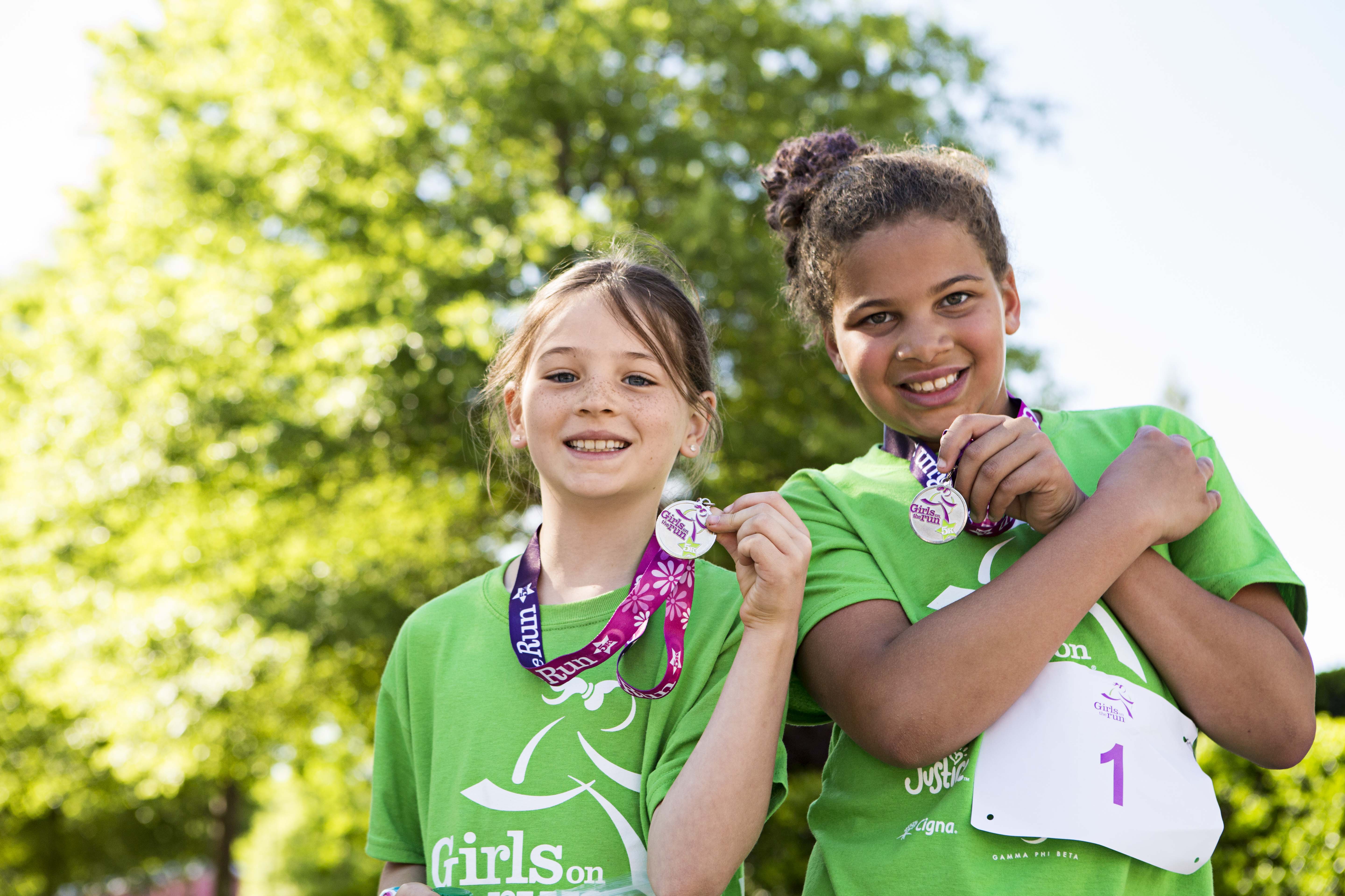 Two Girls on the Run participants smile while showing off 5K medals